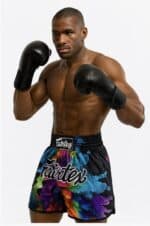 Athletic male boxer wearing colorful shorts and black boxing gloves, ready for a fight.